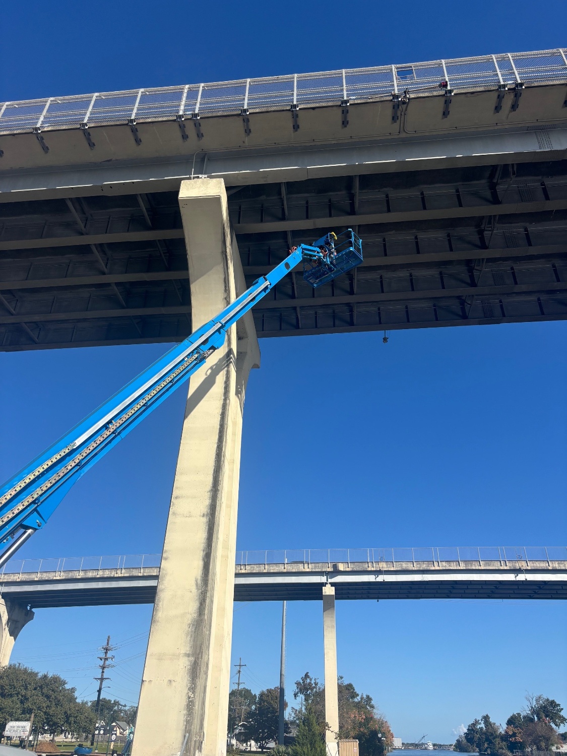 TLP crew working from an aerial lift beneath a highway bridge